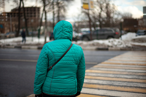 People at pedestrian crossing. Crossing road. Warm jacket at beginning of winter. Winter day in city.