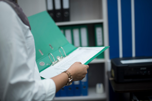 Blue office binder filled with paper on white background