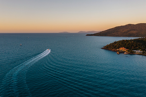 Aerial view of wide ocean landscape with power boat setting out into the sunset, Queensland, Australia
