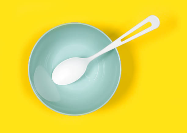 A spoon in a plate. A set of plastic dishes on a yellow background. Modern plastic tableware close-up.
