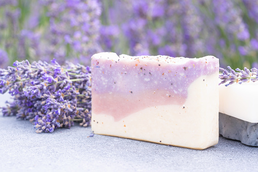 Lavender beauty products - handmade soap with lavender essence against lavender field as background with copy space. Modern apothecary and herbal cosmetics concept. Herbal skincare