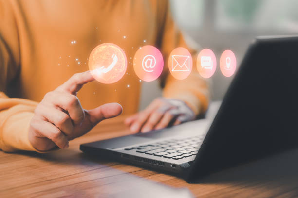 istock Man using a computer laptop and touching on technology virtual screen contact icons ( phone, email, address, live chat, map ). Contact us or Customer support hotline people connect. 1436026372