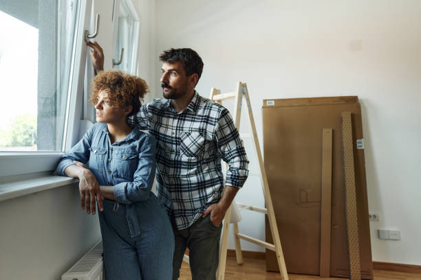 istock Thoughtful couple looking through window at their new apartment. 1436029913