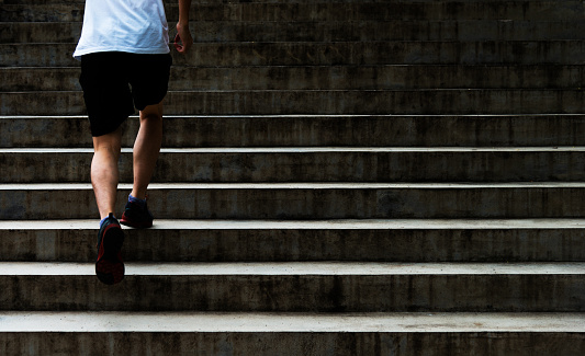 Low section of young man running up outdoor stairs