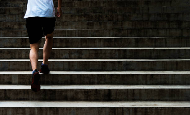 Low section of young man running up outdoor stairs stock photo