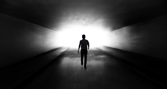 Young man walking through a dark tunnel
