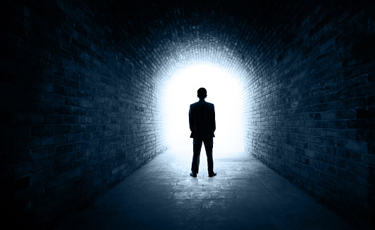 Rear view of businessman standing in a dark tunnel