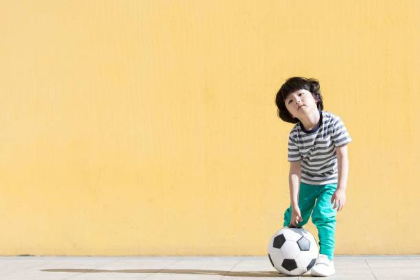 mały chłopiec, który jest fanem piłki nożnej i gra w grę - zdjęcie stockowe - kick stand zdjęcia i obrazy z banku zdjęć
