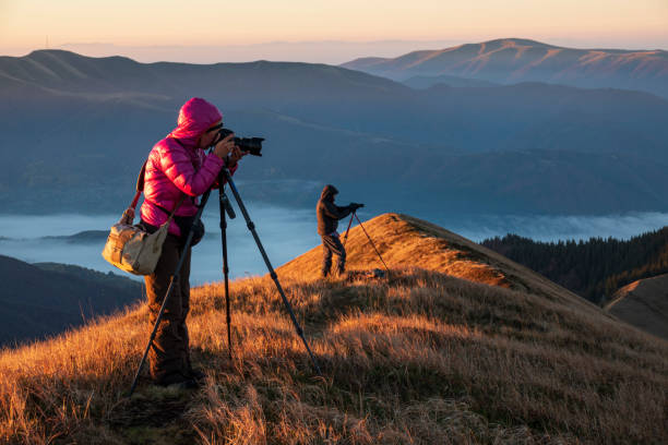 Landscape photographers on the mountain top early in the morning. stock photo