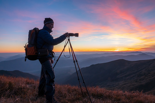 Landscape photographer with the tripod at the sunset. Travel photographer silhouette.