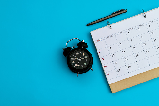 Calendar and alarm clock on blue background