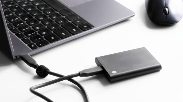 istock External portable SSD drive connected to laptop and computer mouse on white background. Portable Solid State Drive. Concept of modern gadgets and the use of an SSD drive. Selective focus. 1436036319