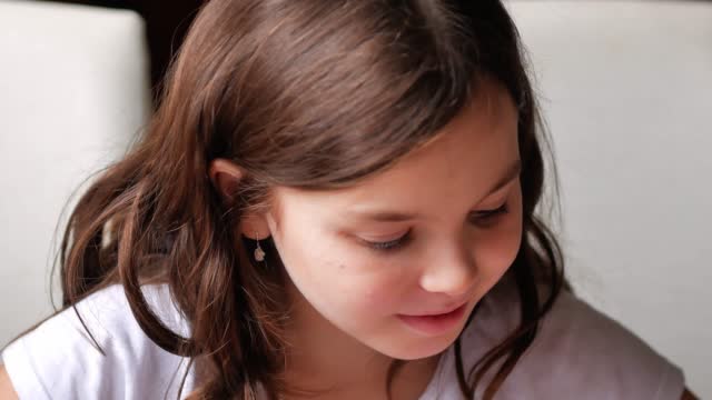 Portrait of a little girl looking seriously to the side, turns her head and looks into the frame, smiles