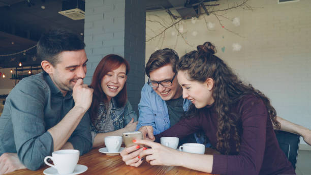 istock Young people are watching smartphone screen discussing photos and laughing during lunch break in cafe. Friendship, modern technology and modern lifestyle concept. 1436038779