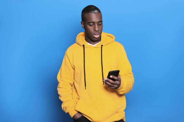 istock Young black man over isolated blue background sending a message with the mobile 1436038819