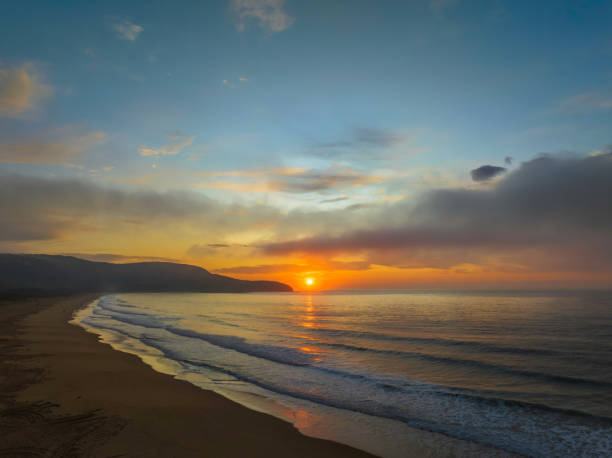 istock Peaceful sunrise over the ocean with small waves and clouds 1436039408