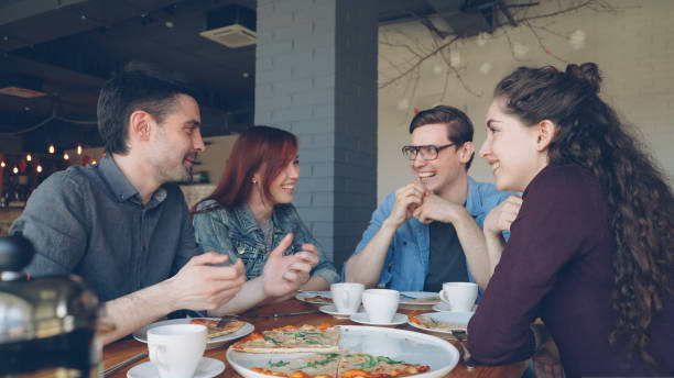 istock Close friends are sharing funny stories gesturing and laughing while having lunch in modern cafe. Positive emotions, happy people and tasty food concept. 1436039414