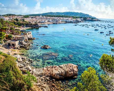 Panoramic view of Calella de Palafrugell old village in a summer morning with a blue sea and sky with a lot of little boats parked in front. Costa Brava, Girona province, Catalonia. Spain
