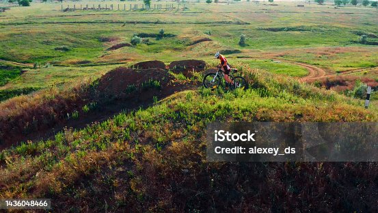 istock Woman in a helmet with a bike goes up the hill in a warm summer day -lovely meadows and fields on the background 1436048466