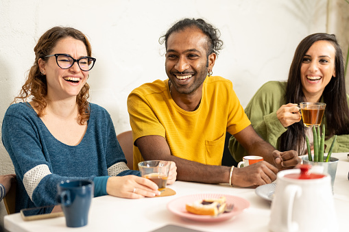 Happy young friends hangout in coffee shop, multiracial university student having fun at breakfast