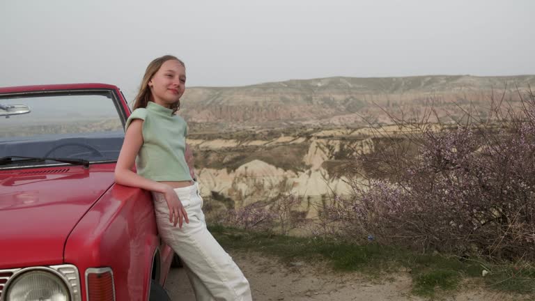 Panning shot of happy girl dancing while relaxing by car