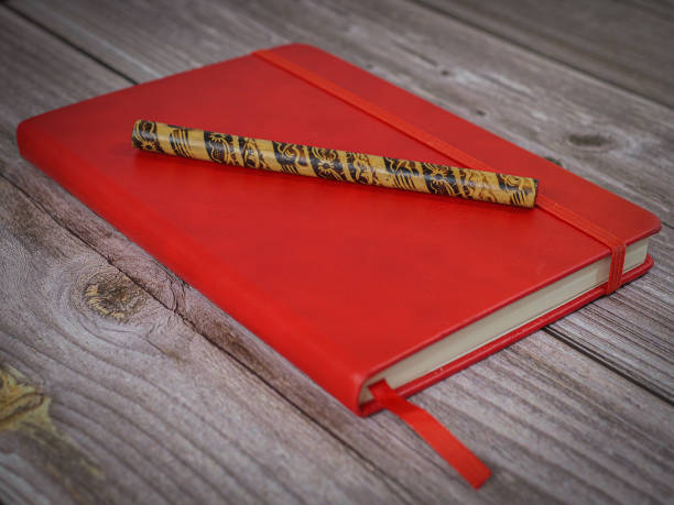 istock red notebook with pen on wooden background. vintage style 1436055560