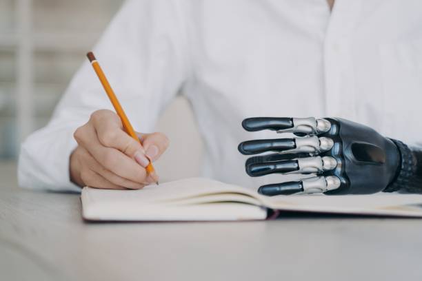 istock Disabled female writing with pencil in notebook, using bionic prosthetic arm, closeup. Medical tech 1436056266