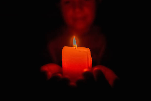 istock Little boy holding red burning candle in the darkness.Selective focus.Closeup. 1436056485