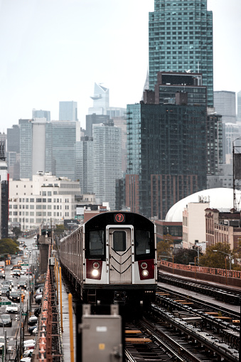 Modern cityscape of Midtown Manhattan on the background while a train of the NYC Subway passing by in the Queens