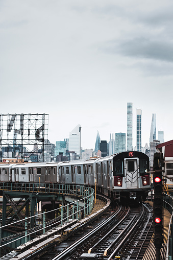 Modern cityscape of Midtown Manhattan on the background while a train of the NYC Subway passing by in the Queens