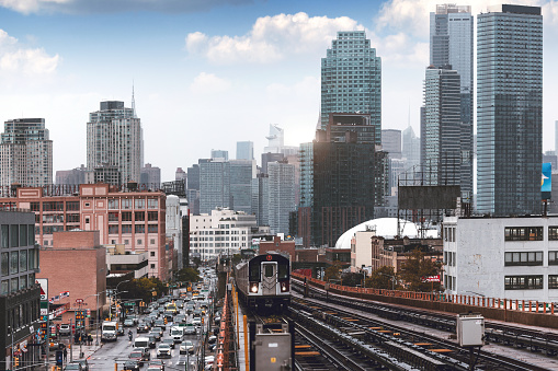 Modern cityscape of Midtown Manhattan on the background while a train of the NYC Subway passing by in the Queens