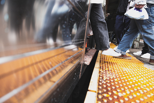Close up on people legs and shoes entering and leaving a train in a subway station in NYC.