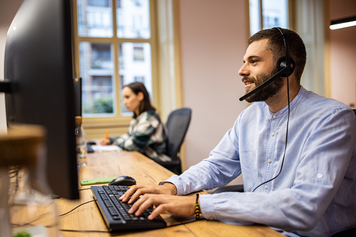 A tech support worker using a computer and a headset in an office
