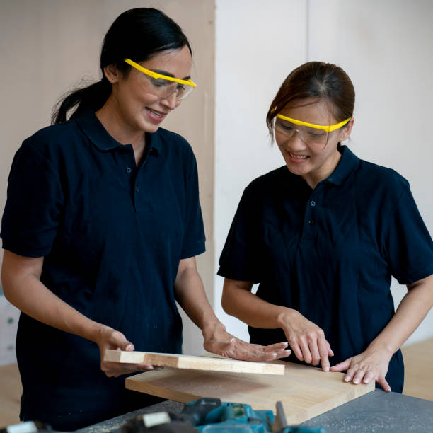 Two women happily working together in carpentry workshop stock photo