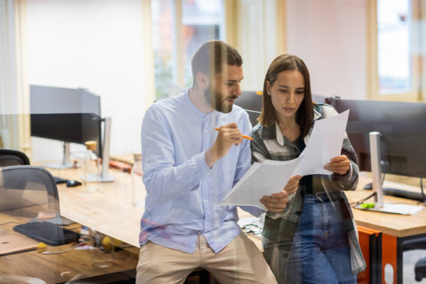 istock Coworkers observing documents and talking in an office 1436060569