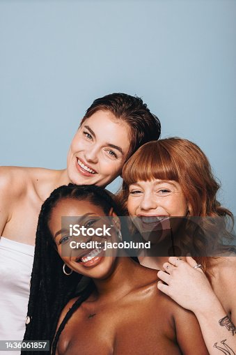 istock Happy women with different skin tones smiling at the camera in a studio 1436061857