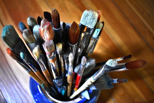 A closeup of the artist's paintbrushes in the blue vase.