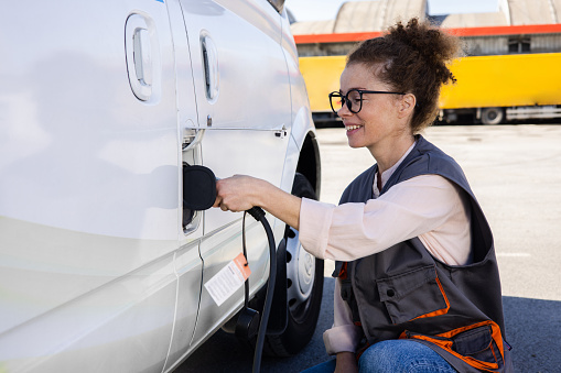 Portrait of a female worker on a charging station charging an electric van