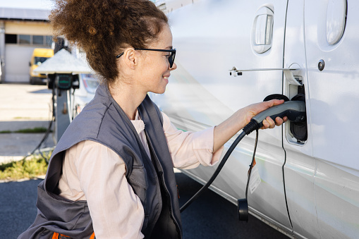 Portrait of a female worker on a charging station charging an electric van