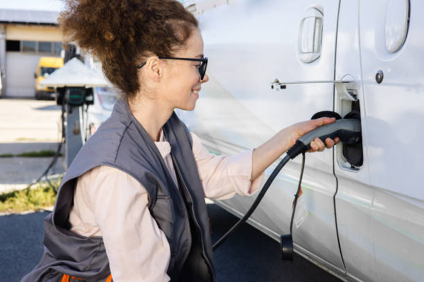 Portrait of a young female worker charging electric van stock photo
