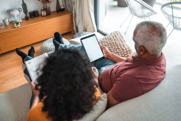istock Mature Hispanic Male Using A Digital Tablet While Spending Time With His Wife At Home 1436063924