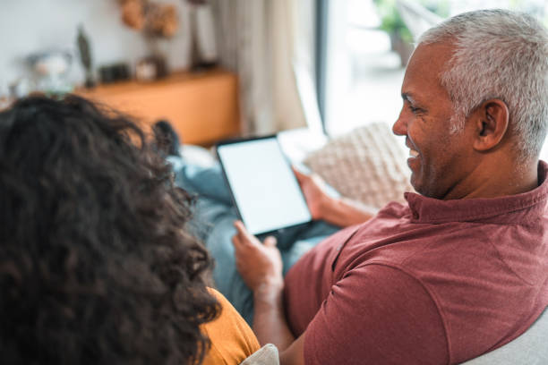 istock Mature Hispanic Male Using A Digital Tablet While Spending Time With His Wife At Home 1436063930