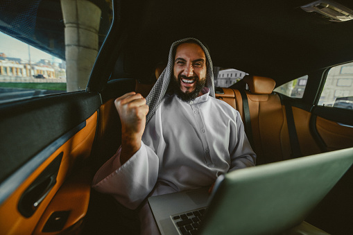 Working. A suadi businessman working on a laptop in a car