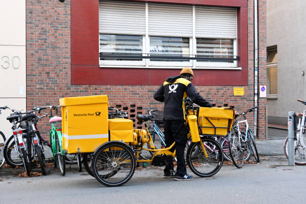 Muenster, Germany, October 18, 2022 - Deutsche Post letter carrier delivering mail with an electric bike