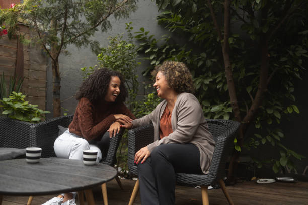 Coffee with mother Shot of a young African-American woman bonding with her mother. They sit on the patio and have a coffee. black mother and adult daughter stock pictures, royalty-free photos & images