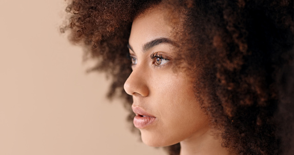 Face, beauty and black woman, afro hair or hair care on brown studio background. Model, makeup cosmetics and female from South Africa thinking or contemplating with natural skin and skincare closeup