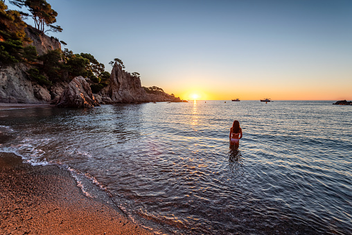Woman in bikini enjoying the Sunrise in Costa Brava with the feet into water