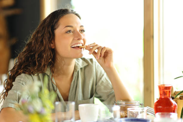 szczęśliwa kobieta jedząca ciasteczko w restauracji - cookie food snack healthy eating zdjęcia i obrazy z banku zdjęć