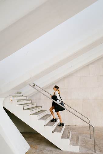 Young busy stylish professional woman going to her job carrying a coffee.