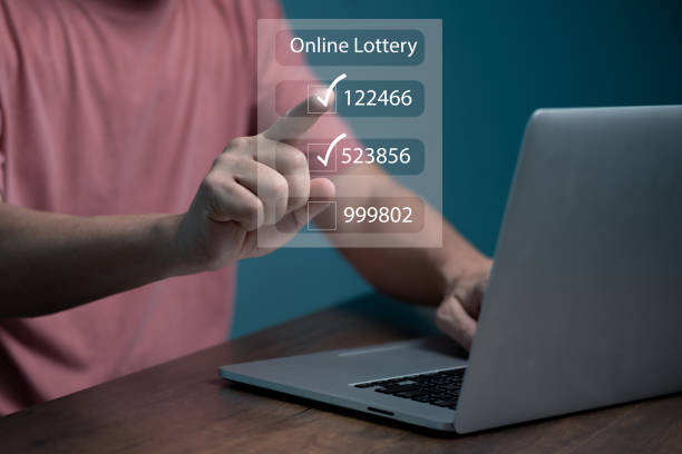 istock Man using computer and touching on virtual Online lottery screen to buy two number set. 1436077767